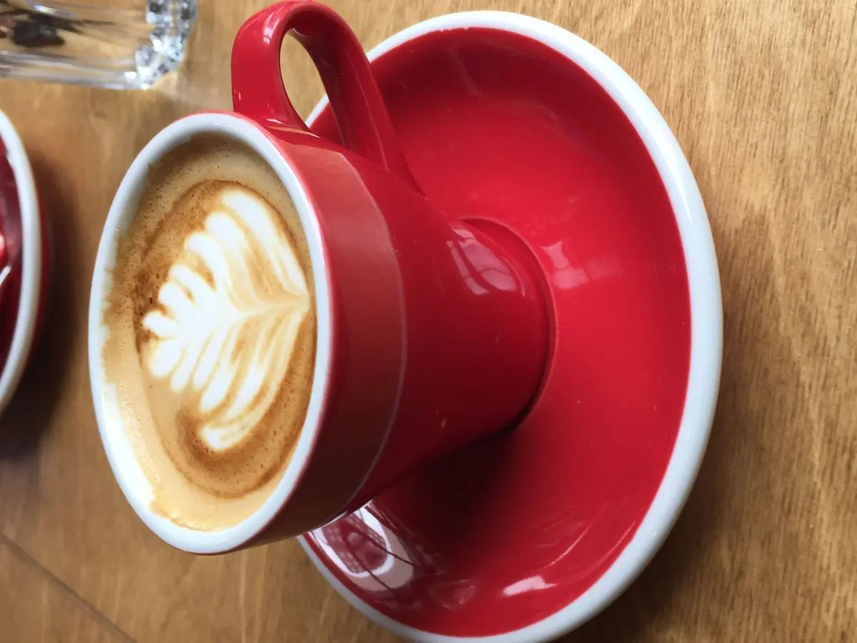 Latte Art in einer roten Tasse, aufgenommen in einem Specialty-Coffee-Café